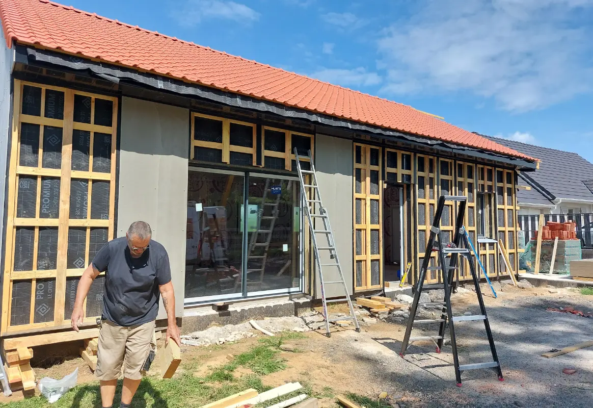 photo illustre la maison avec sa toiture en tuiles rouges terminée et la préparation du bardage bois (ossature secondaire fixée sur les murs, Audomar'Bois Saint-Omer (62)